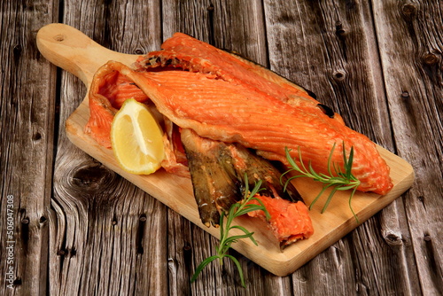 Hot smoked salmon bones on wooden kitchen board. Dark wooden board background