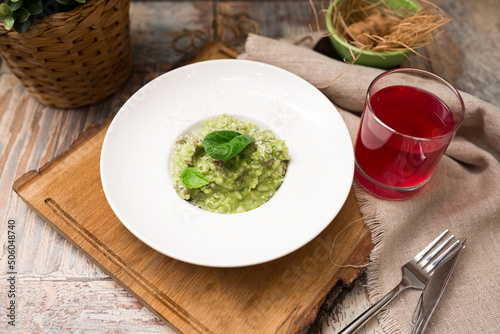 Plate serving of green risotto with basil leaves and cheese. Healthy food. Tender arborio flavored with spinach greens and infused with lamb meat broth photo