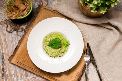 Plate serving of green risotto with basil leaves and cheese. Healthy food. Tender arborio flavored with spinach greens and infused with lamb meat broth