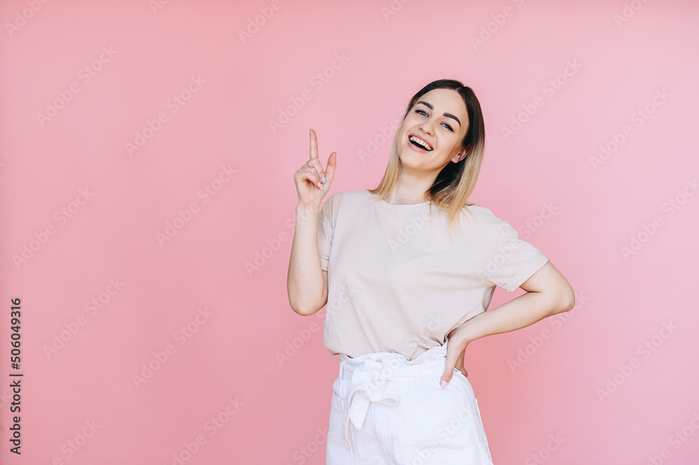 Portrait of a woman points her index finger at a free space on the background and smiles broadly Portrait of a woman points her index finger at a free space on the background and smiles broadly