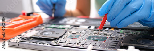 Foto Laptop repair, hands hold voltage meter for electronics