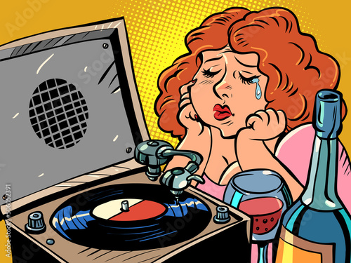 Sad red-haired woman listens to music on the gramophone and drinks wine. Lonely evening. Plate