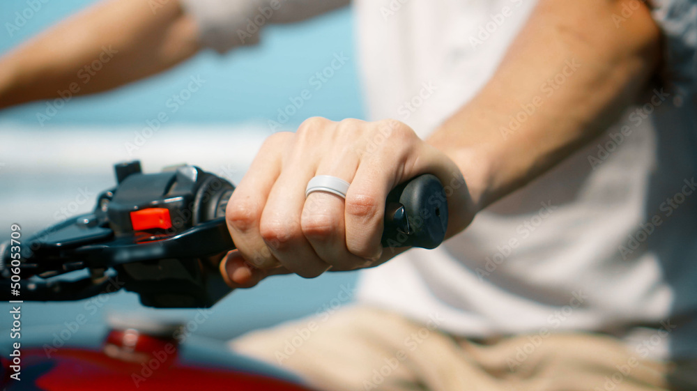European young man hold motorbike handlebars while touching gas handle and brake lever ahead of trip European young man hold motorbike handlebars while touching gas handle and brake lever ahead of trip