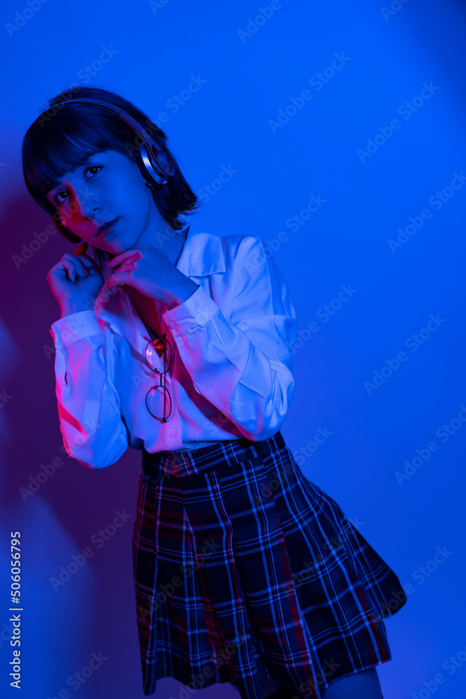 Fototapeta premium Cheerful ecstatic young woman in hoodie keeping eyes closed and laughing while enjoying music in headphones, studio shot 