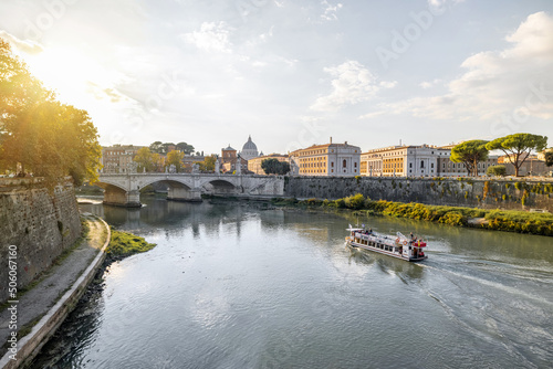Landscape of Tiber river with boat at sunny morning in Rome. Dome of famous saint Peter basalica on the skyline. Traveling Italy photo