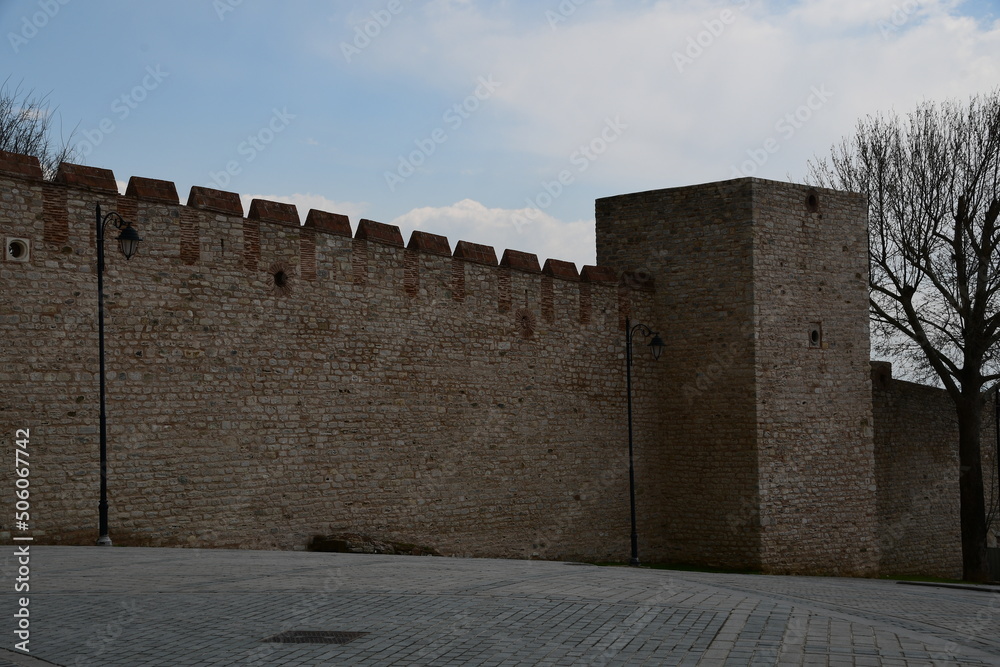 Fragment of a high fortress wall made of stones. Square tower in the wall of the fortress