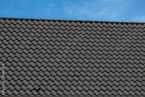 Dark grey or black brick rooftop under blue sky and white cloud, Tiles background details, Shingles texture, Abstract geometric pattern, Roof brick material. photo