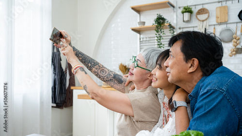 Self-portrait selfie of cheerful excited glad ecstatic Asian family taking Photograph with mobile phones in the kitchen.The joy of Thai home cooking together.Celebrate in ester,Christmas eve,Holiday.