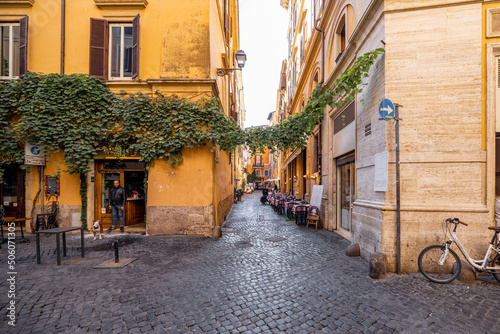 Fototapeta Naklejka Na Ścianę i Meble -  Narrow street with cafe and small shops in Rome. Italy travel concept, visiting cozy places