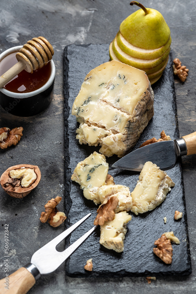 Fototapeta premium Blue cheese with pears, walnuts, nuts and honey. French cuisine. Vegetarian lunch. vertical image. top view. place for text