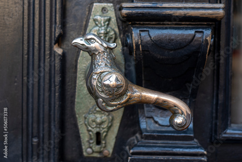 Old door handle. Wooden vintage entrance door with antique door handles in the shape of bird. Selective focus