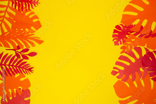 Fototapeta Naklejka Na Ścianę i Meble -  red and orange jungle leaves on the left and right of the yellow background, in the middle copy space, creative exotic design, flat lay, jungle party