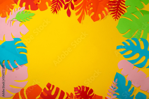 yellow background for copy space surrounded by colorful jungle leaves, creative summer tropical design, flat lay