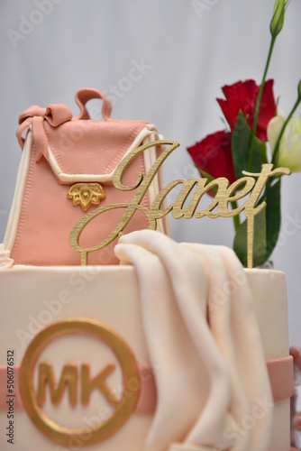 Pink and peach cake with Janet topping and handbag to show style and elegance for a birthday party. shot against white draping sheets with soft lighting