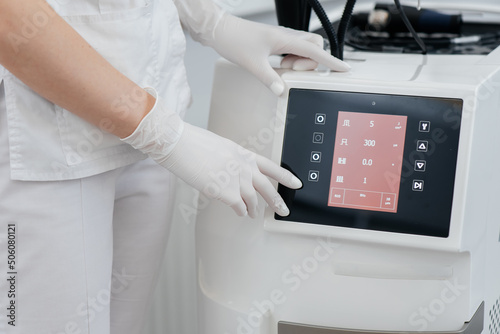 The cosmetologist's hand adjusts a modern laser in a beauty salon close-up. Laser pulses cleanse the skin. Hardware cosmetology. The process of photothermolysis, warming the skin.