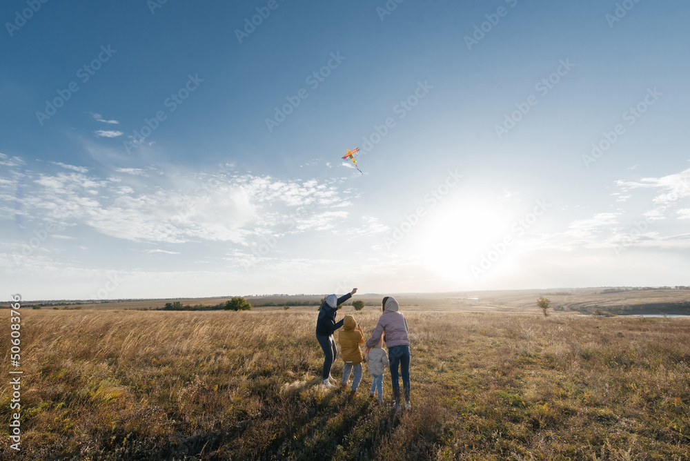 A happy family with children flies a kite and spends time together outdoors in a nature reserve. Happy childhood and family holidays. Freedom and space.