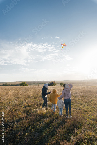 A happy family with children flies a kite and spends time together outdoors in a nature reserve. Happy childhood and family holidays. Freedom and space.