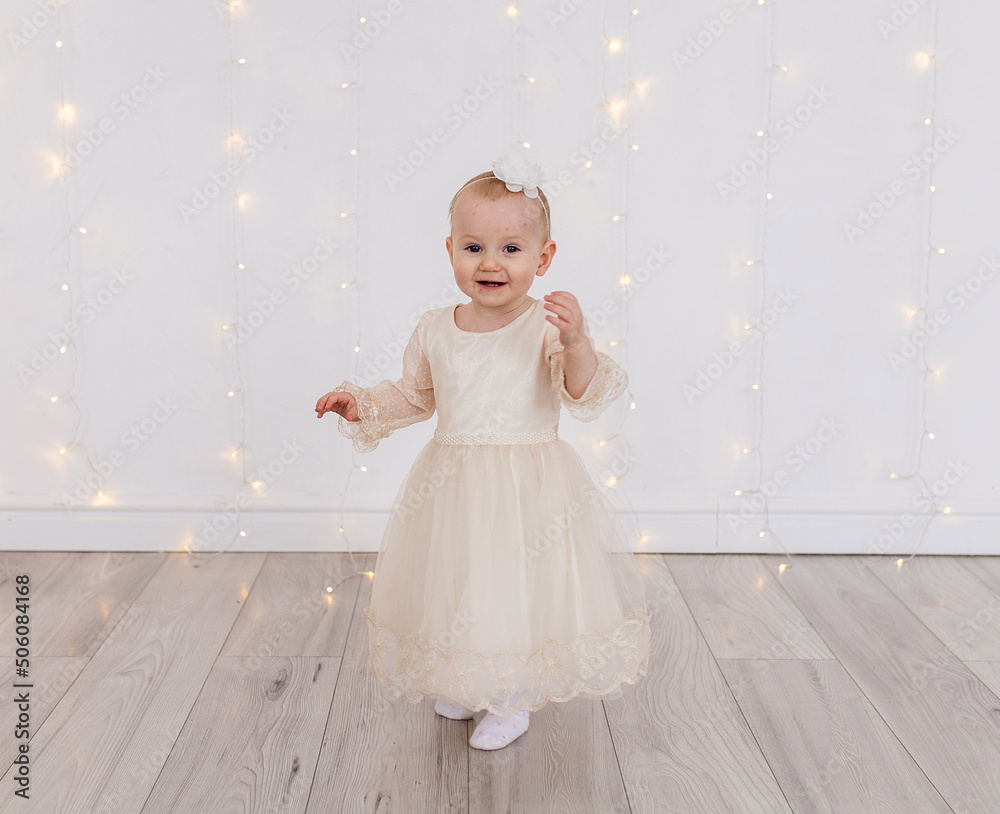 Little girl in a light lush dress on a background of Christmas bokeh. Little girl in a light lush dress on a background of Christmas bokeh.