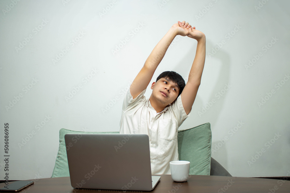 Remote work concept, Male freelancer stretching to relax and drink coffee after working at home