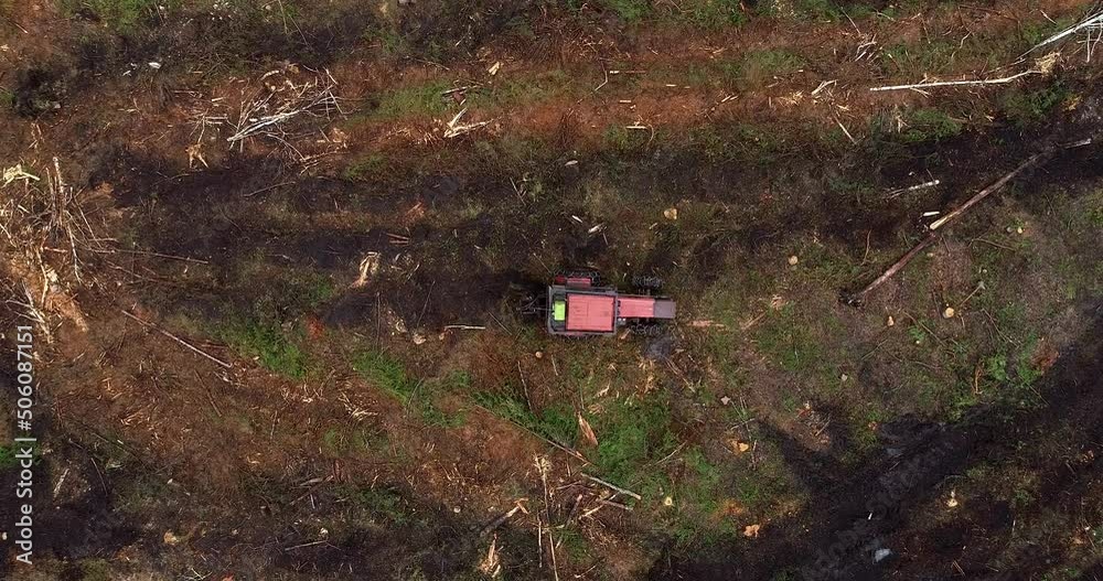 An aerial of a red tractor preparing forest land with disc trenchers for planting saplings. An aerial of a red tractor preparing forest land with disc trenchers for planting saplings.