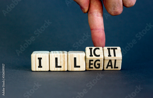 Illegal or illicit symbol. Businessman turns wooden cubes and changes the concept word Illegal to Illicit. Beautiful grey table grey background. Business and illegal or illicit concept. Copy space.