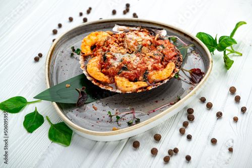 Shrimps baked in scallop shell with tomato sauce and vegetables