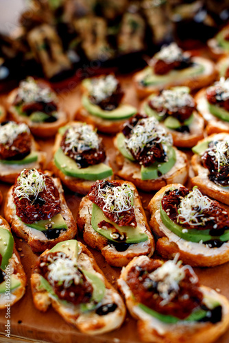 Sandwiches and tartlets with sun-dried tomatoes, avocado, cheese and balsamic vinegar. soft focus