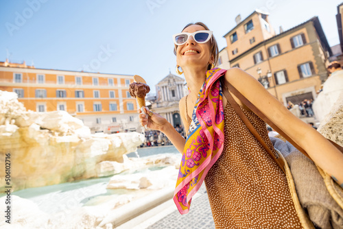 Photography Woman eating ice cream in cone while visiting famous di Trevi fountain in Rome