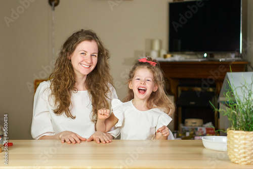 Have fun together. Smile and laugh at home. Happy family at table. Motherhood is joy. Children laughter. Kid play. woman babysitter is good for sister. White dresses on caucasian women. tickles girl