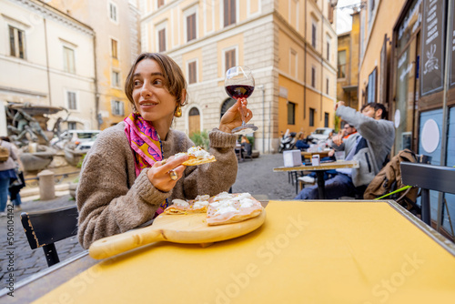 Canvas Print Woman eating pizza and drinking wine at restaurant on a street in Rome