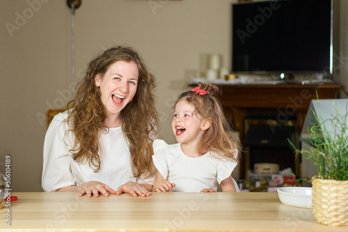 Have fun together. Smile and laugh at home. Happy family at table. Motherhood is joy. Children laughter. Kid play. woman babysitter is good for sister. White dresses on caucasian women. tickles girl