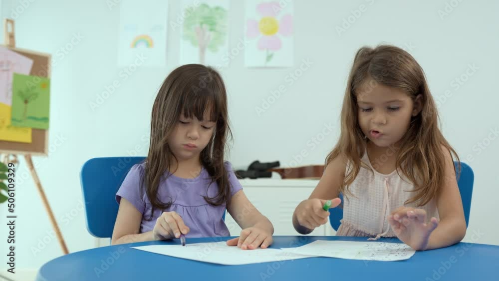 Two children draw together at table indoors with colored pen. Kindergarten playtime activities. First time to school education and play in kindergarten, or preschool child study at home concept. Two children draw together at table indoors with colored pen. Kindergarten playtime activities. First time to school education and play in kindergarten, or preschool child study at home concept.