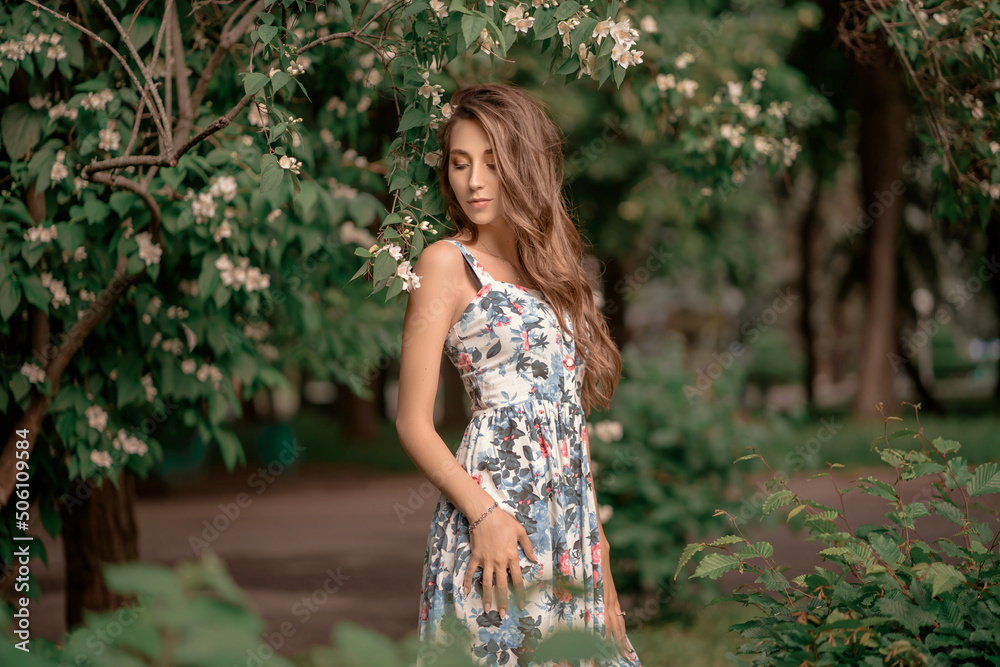 Portrait of a beautiful young girl with long hair in a dress among flowers Portrait of a beautiful young girl with long hair in a dress among flowers