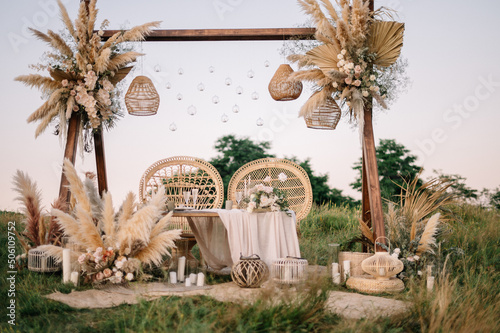 Fabulous wedding for two. Wedding table set up in boho style with pampas grass and greenery, and two straw chair in field with sunset view