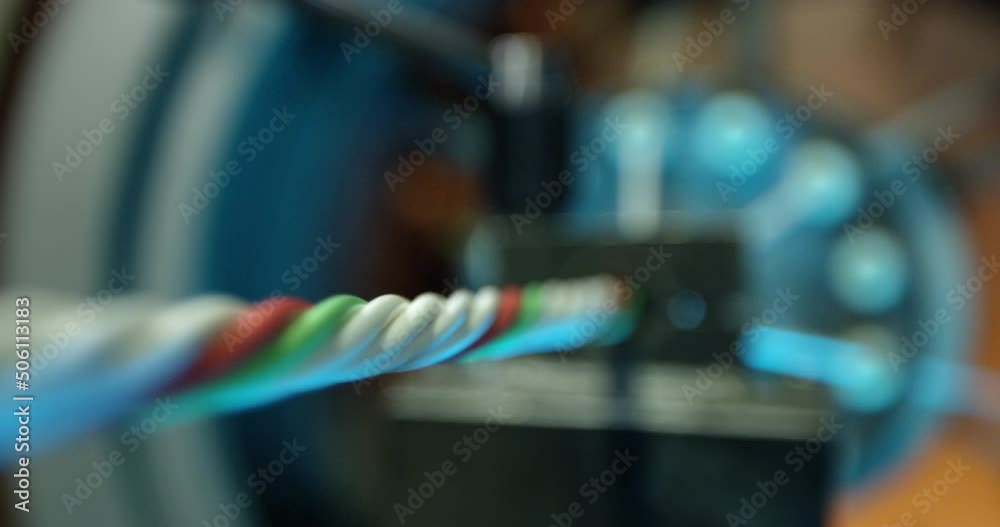 Production of electric cable. The output of the finished multicolored cable at the final stage of manufacture. Taking a close-up of the cable against the background of a foggy image of a rotating