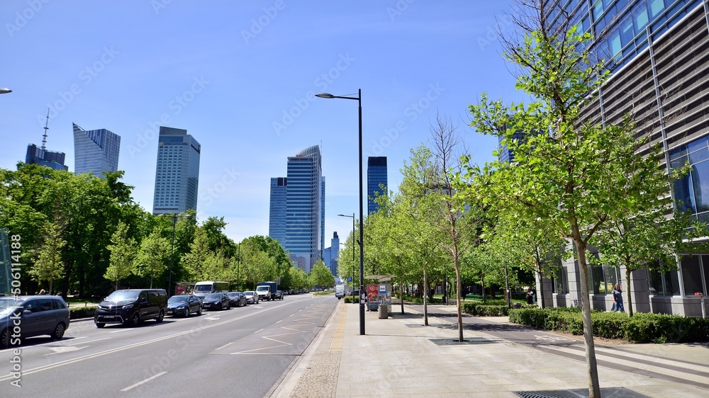 Glass skyscrapers against the blue sky and traffic in the city center. Colorful cityscape with buildings architecture and cars on the street. Sunny weather in the city.