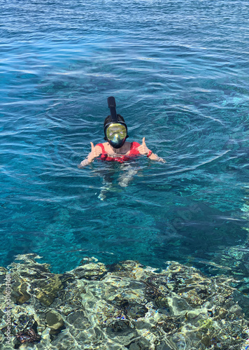 Happy young woman swims in a mask. Snorkeling, fish watching.