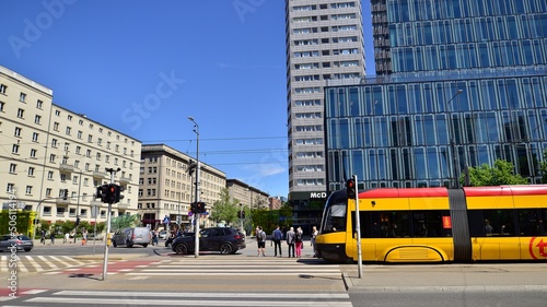 Colorful cityscape with building architecture and street transportation in the center. Glass skyscrapers against the blue sky and traffic in the city center. Sunny weather in the city.