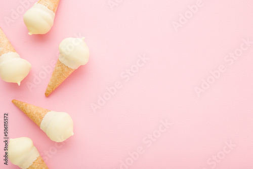 Waffle cones of white vanilla ice cream on light pink table background. Pastel color. Closeup. Cold sweet snack in summer. Empty place for text. Top down view.