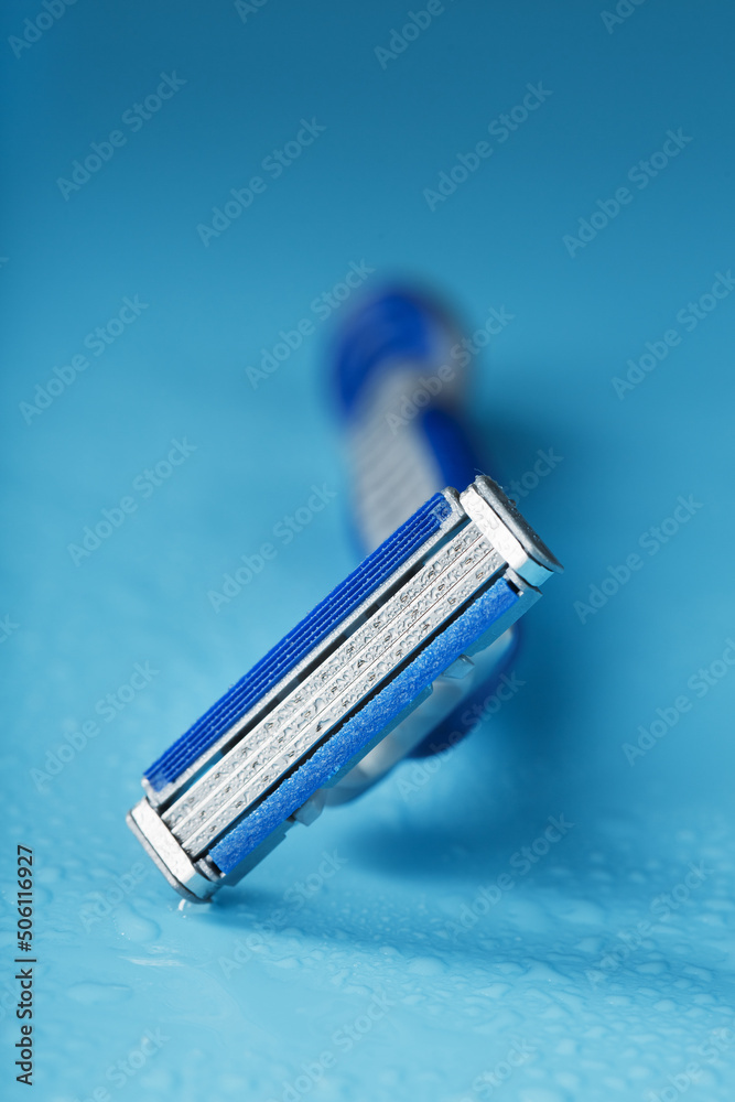 Razor blades on a blue background with drops of icy water