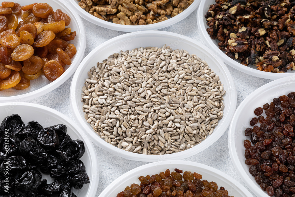 Various dried fruits, nuts and sunflower seeds lie on round plates on a light background. The concept of a healthy healthy diet. Source of vitamins, vegetable proteins and fats, oils. Various dried fruits, nuts and sunflower seeds lie on round plates on a light background. The concept of a healthy healthy diet. Source of vitamins, vegetable proteins and fats, oils.