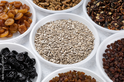 Various dried fruits, nuts and sunflower seeds lie on round plates on a light background. The concept of a healthy healthy diet. Source of vitamins, vegetable proteins and fats, oils.