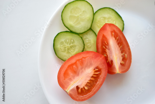 Sliced red tomatoes and green cucumber close-up on a plate