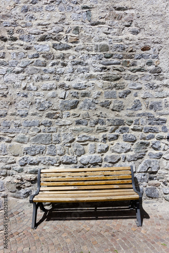 Vecchia panchina di legno accostata ad un muro in pietre antico