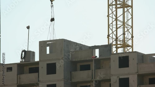 Motion of a crane transporting block on the building. Process of building a skyscrapper. White sky background. photo