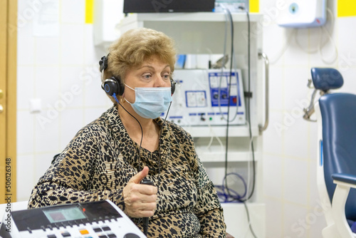 Audiologist checks the hearing of an older woman photo