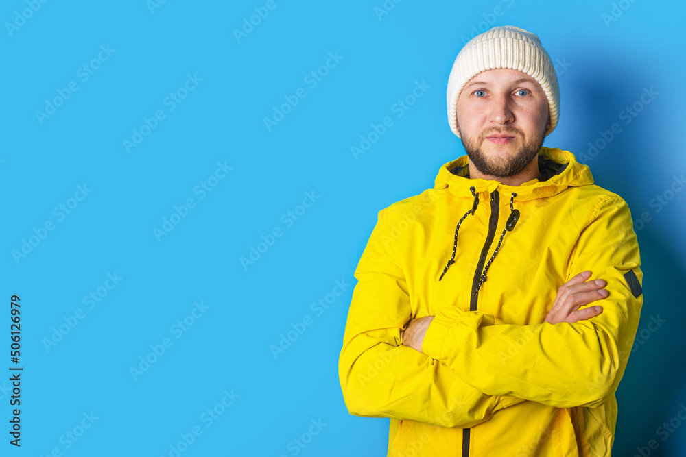 Young man in a yellow jacket with crossed arms on a blue background Young man in a yellow jacket with crossed arms on a blue background