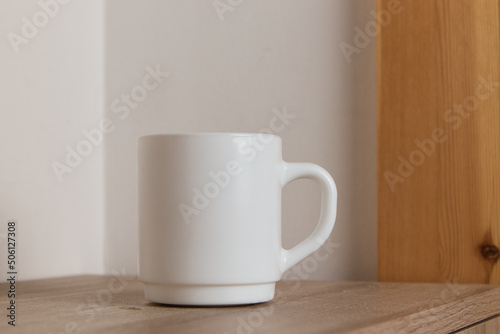 White mug for tea and coffee in on a wooden table, close-up