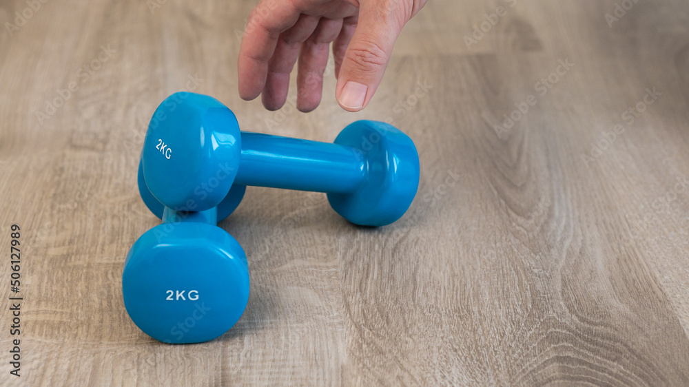 Blue dumbbell in man's hand for doing fitness workout exercises at home. Blue dumbbell in man's hand for doing fitness workout exercises at home.