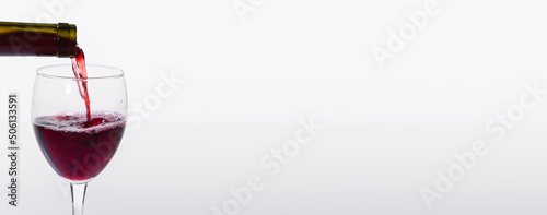 Pouring red wine into glass banner on white background with copy space and place for advertising, close-up